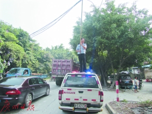 民警罗德平在烈日下托举电线保障车辆通行获赞。（网友拍摄）