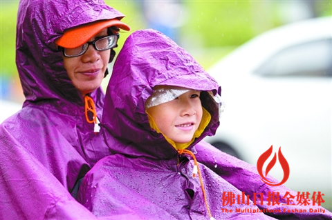 昨日,高明中山路上,一对母女在雨中等红绿灯。/佛山日报见习记者吕润致摄