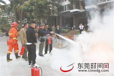 小区居民跟消防队员学习使用灭火器