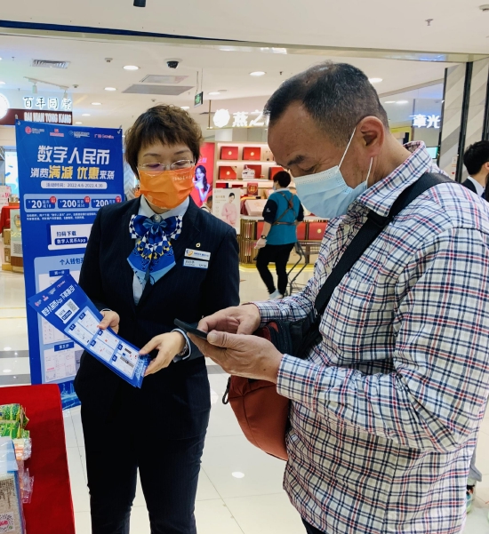 建行工作人员为市民介绍数字人民币消费满减优惠活动