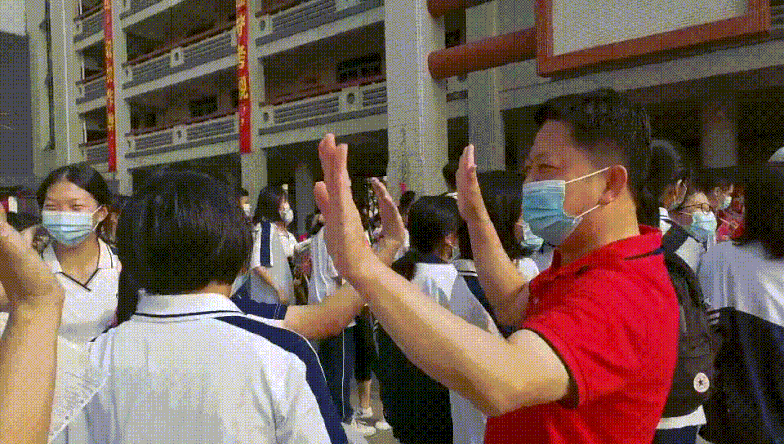 送考现场,老师与考生击掌鼓励,传递能量。