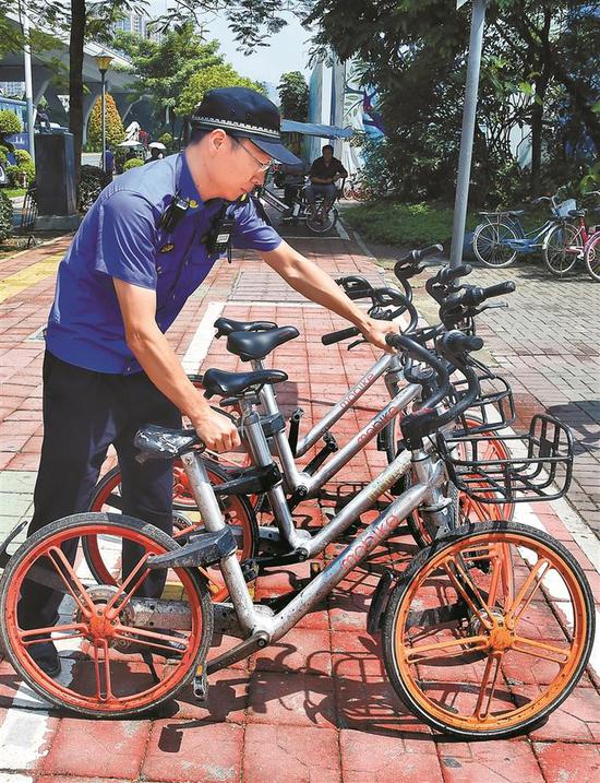 ▲执法队员在公共场所整理违规停放的共享单车。深圳晚报记者 冯明 摄