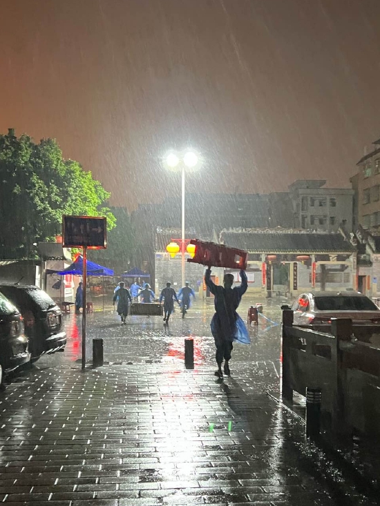 上图：队员们冒雨运送抗疫物资