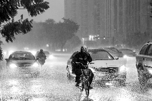 在暴雨中骑行的人。信息时报记者 康健 摄