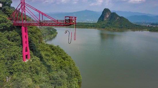 飞龙蹦极跳台建于狮子山腰,俯视千亩天然天鹅湖湖景,蹦极主体呈朱红色,跳台延伸湖面51米,悬空高度63米,超过23层楼高度,360°超大摆弧,20米大摆径、30米高荡绳、15米高空反弹及3重安全保险层层保护。