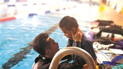 潜水教练和自闭症孩子在泳池边交流。
