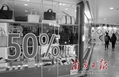 今年2月，香港铜锣湾一家店铺减价促销，顾客从附近经过。新华社发