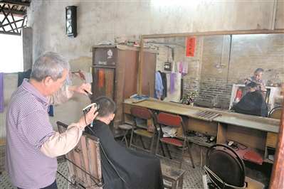 昭叔在简陋的理发店里为孩子理发。