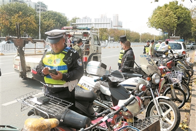 交警查处地铁站口的摩托车和电动自行车。