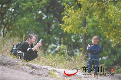“来，摆个Pose！” 榴花公园里，一位女士正在给小朋友拍照 （记者 李梦颖 摄）