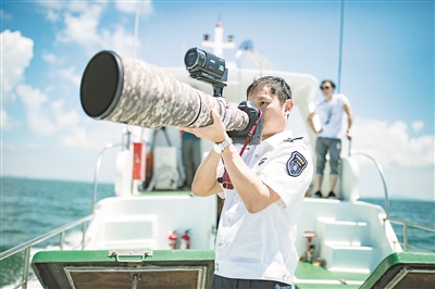 保护区工作人员手持长镜头拍摄中华白海豚。