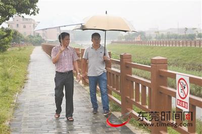 莫文辉（左）和联络员在雨中巡查石水口排渠 东莞时报记者 陈栋 摄