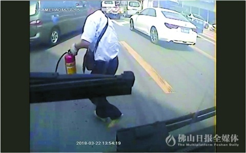 视频中，梁忠栋手提灭火筒冲向冒烟起火的小汽车。受访者供图