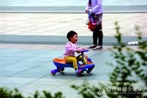 昨日，天气和暖，三水区西青大道一小区门口，一孩子在玩扭扭车。/佛山日报记者陈浩森摄