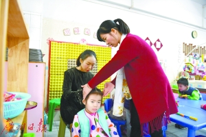 吴敏玲在给小朋友扎辫子,其妈妈在一旁指导。