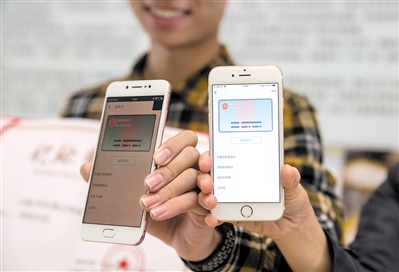 首批成功开通网络身份证的两位市民在手机上展示网络身份证。