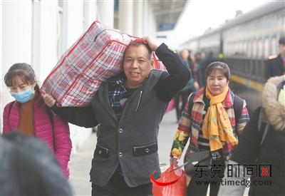 东莞东火车站，旅客扛着行李准备乘车返乡（记者 陈栋 摄）