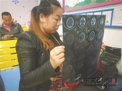 凡凡的母亲龙女士在查看孩子的脑部CT片（记者 陈栋 摄）