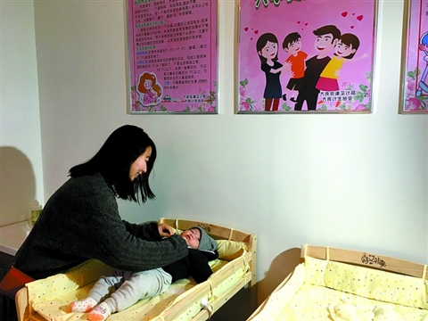 一位年轻妈妈正在母婴驿站里帮宝宝整理衣服。