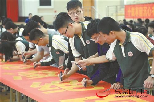 百日誓师现场，塘厦中学高三学生在横幅上签名 学校供图
