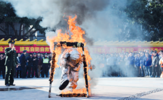 消防官兵向参加消防演习的员工展示如何穿着消防服穿越火场。/珠江商报通讯员梁东江摄