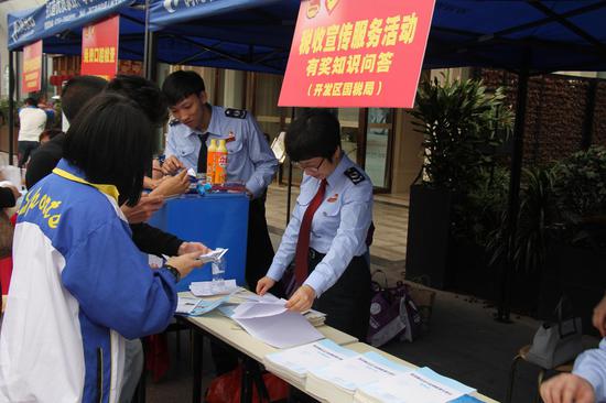 青少年喧闹到场税收知识问答活动,两名中学生用手机查阅税收知识