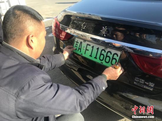 11月20日,长春市民为爱车安装新能源汽车专用号牌。 中新社记者 张瑶 摄