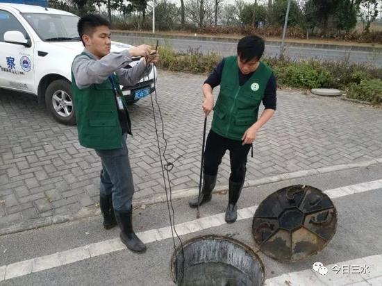 乐平镇环保执法人员对管网污水进行采样监测。