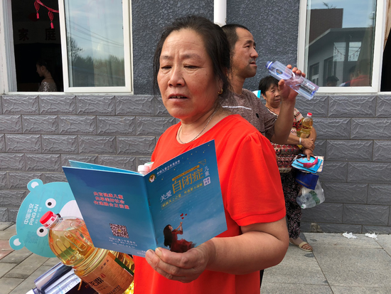村民在活动现场认真阅读关爱自闭症儿童科普读本