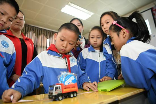 四川南充蓬安县城东路小学学生正在“儿童平安·小课堂”动手操作超载模拟实验