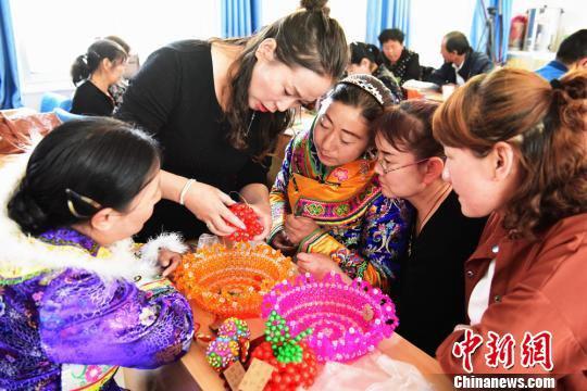 连日来,甘肃张掖市肃南裕固族自治县开展核心区搬迁农牧民手工艺品制作生产技能培训班,裕固族妇女学习制作手工艺品。 武雪峰 摄