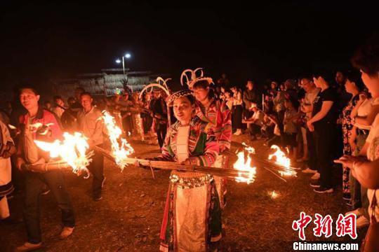 图为白马人穿戴民族服饰相约来到村广场准备将手中未燃尽的火把聚集起来点起篝火。 杨艳敏 摄