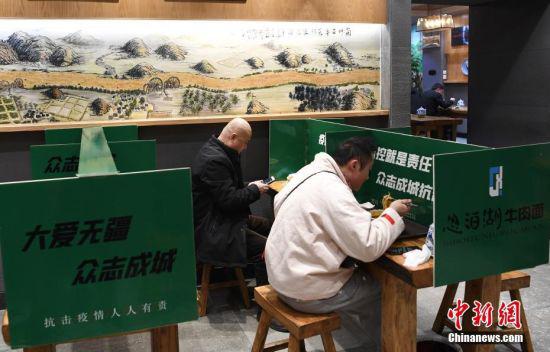 2月19日,甘肃省兰州市一家牛肉面馆设立格挡餐区,市民分开就餐。
