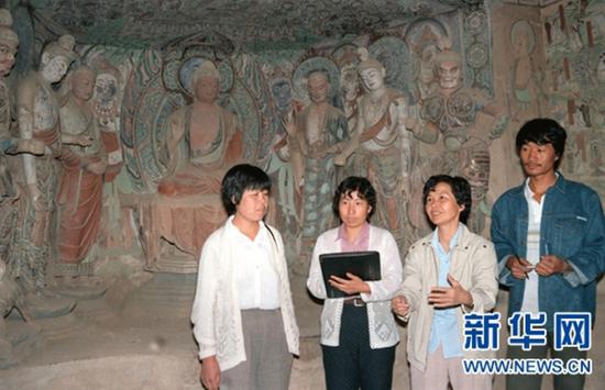 1994年3月10日,敦煌研究院副院长樊锦诗(右二)向青年同志介绍石窟艺术。新华社记者 张生贵 摄