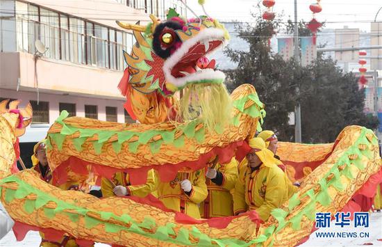 2月18日,社火队员在兰州市皋兰县县城街道表演舞龙。 新华社记者 范培珅 摄