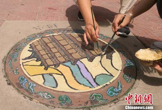 图为在井盖绘画。 刘玉桃 摄