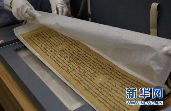 敦煌市档案馆工作人员展示修复后的唐代藏文写经。新华网发(张晓亮 摄)