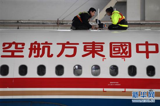 1月4日,在东航技术甘肃分公司机库,师父杨杰男给杨佳郁(左)讲解飞机发动机舱构造。