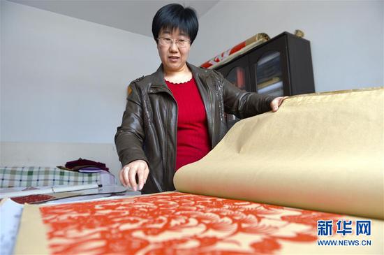 1月10日,惠富君在甘肃省庆阳市镇原县的家中展示自己的剪纸作品。 新华社记者 李笑 摄