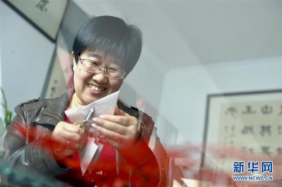 1月10日,惠富君在甘肃省庆阳市镇原县的家中剪纸。