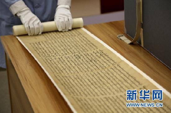 敦煌市档案馆工作人员展示修复后的唐代藏文写经。新华网发(张晓亮 摄)