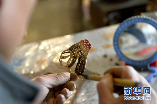 3月13日,潘明生的徒弟周治兵在甘肃省定西市渭源县新寨镇为皮影上色。新华社记者李笑摄