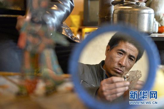 3月13日,潘明生的徒弟周治兵在甘肃省定西市渭源县新寨镇刻皮影。新华社记者李笑摄