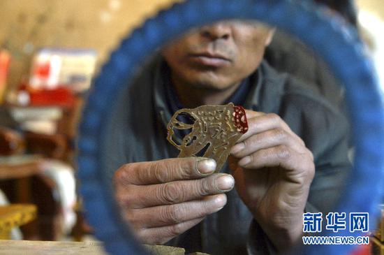 3月13日,潘明生的徒弟周治兵在甘肃省定西市渭源县新寨镇为皮影上色。新华社记者李笑摄