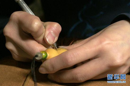 这是4月1日在兰州刻葫芦传习所拍摄的甘肃省工艺美术大师阮琳雕刻的葫芦作品《心经》与一小撮米粒的对比图。 新华社记者 范培珅 摄