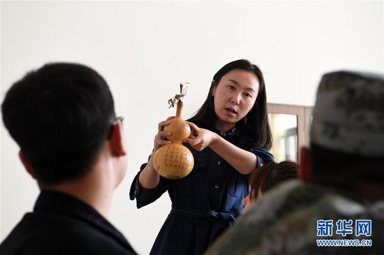 在兰州职业技术学院非物质文化遗产学院,兰州阮氏雕刻葫芦艺术第四代传人阮熙越给学生讲解雕刻葫芦技巧(4月1日摄)。