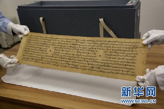 敦煌市档案馆工作人员展示修复后的唐代藏文写经。新华网发(张晓亮 摄)