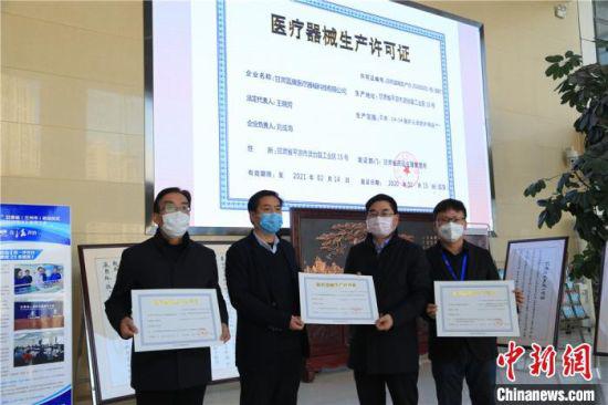 图为甘肃省药品监督管理局副局长王宗伟(右二)为3家防护服生产企业代表发放临时医疗器械注册生产许可证。这意味着,甘肃填补了医用防护用品生产的空白。 史静静 摄