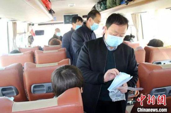 图为交通运输部门工作人员为返岗务工人员发放途中更换的防疫口罩。 甘肃省交通运输厅供图