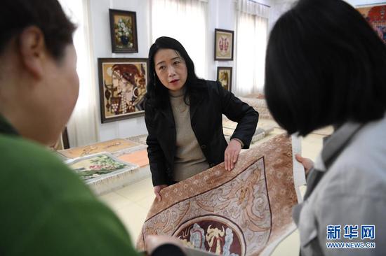黄晶蓉(中)在天水新天丝毯有限公司的成品展室里和徒弟交流丝毯织造技艺(4月14日摄)。新华社记者 陈斌 摄